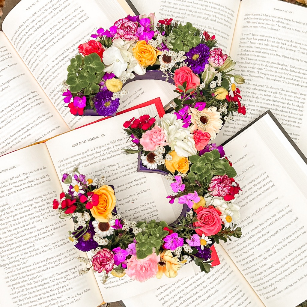 Cardboard floral number 3 surrounded by open books